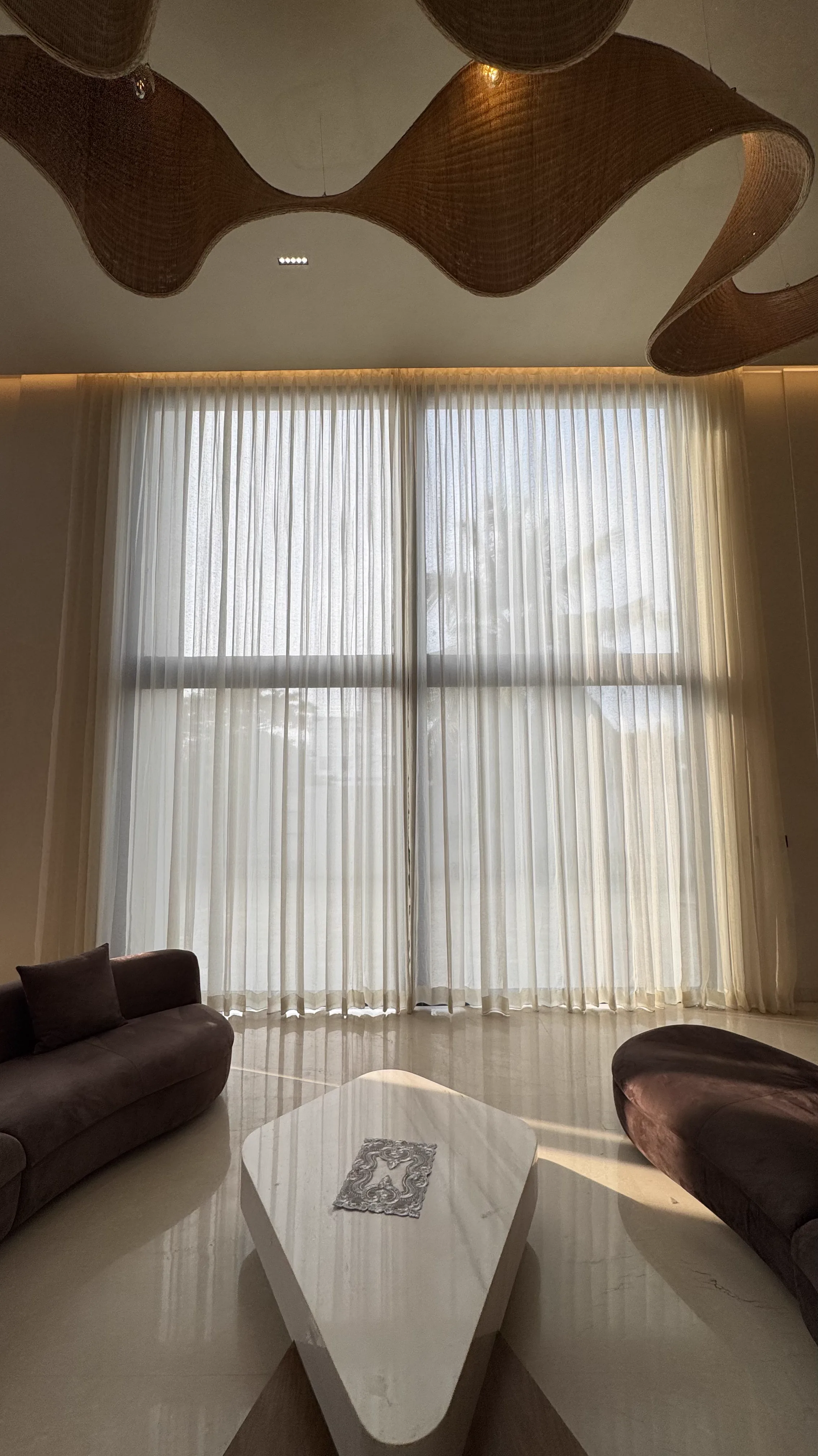 Sheer curtains in a living room with a wave-form wood ceiling