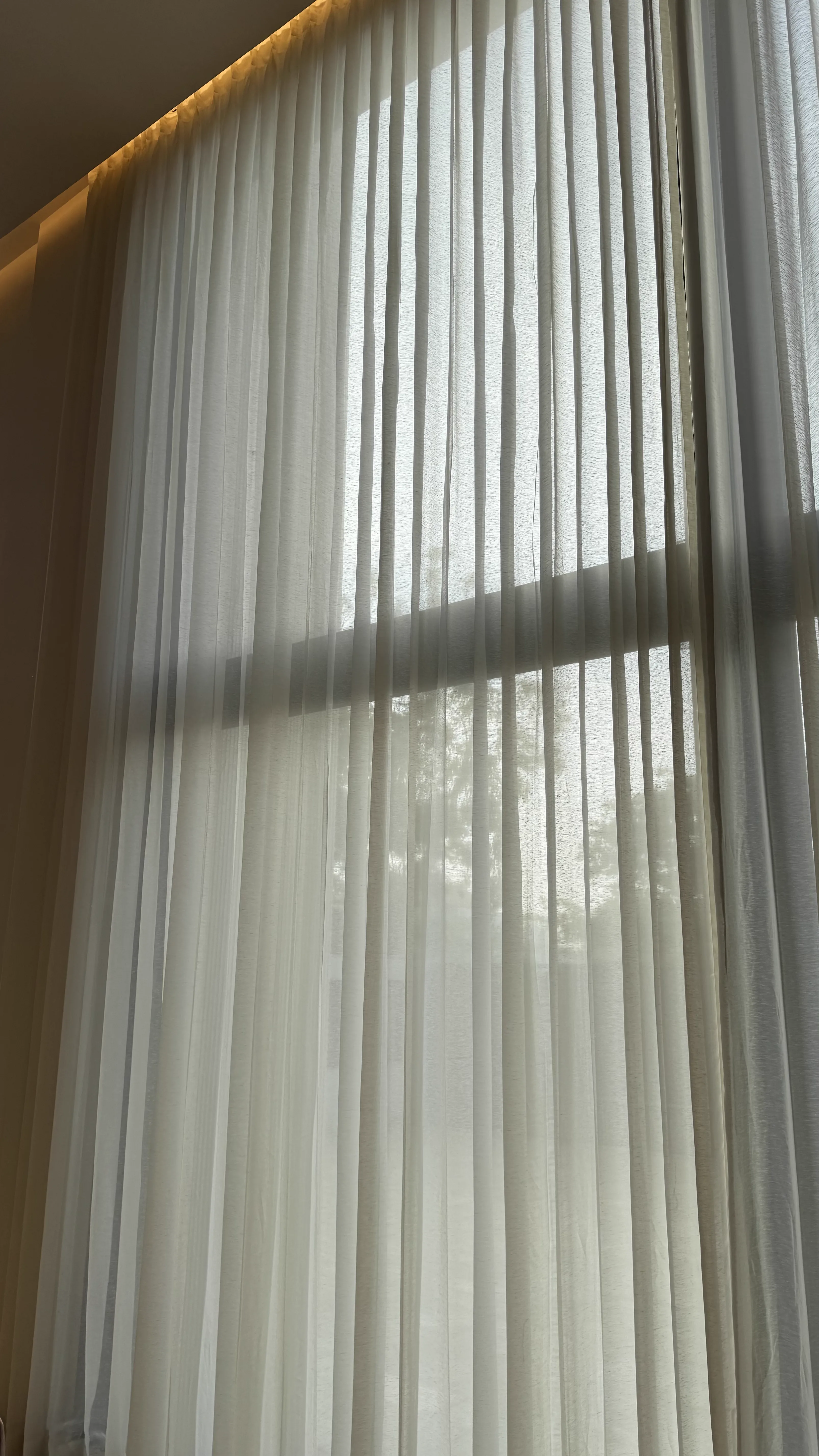 White sheer curtains lit by warm cove lighting