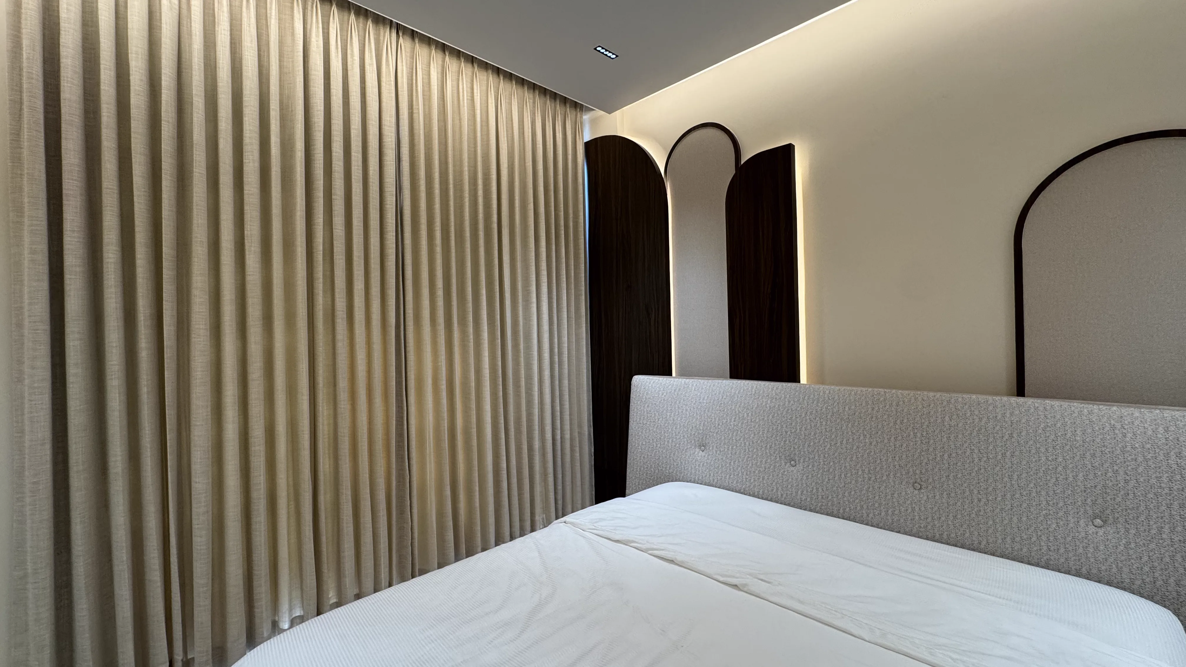 Arched fluted headboard panels behind a cream bed