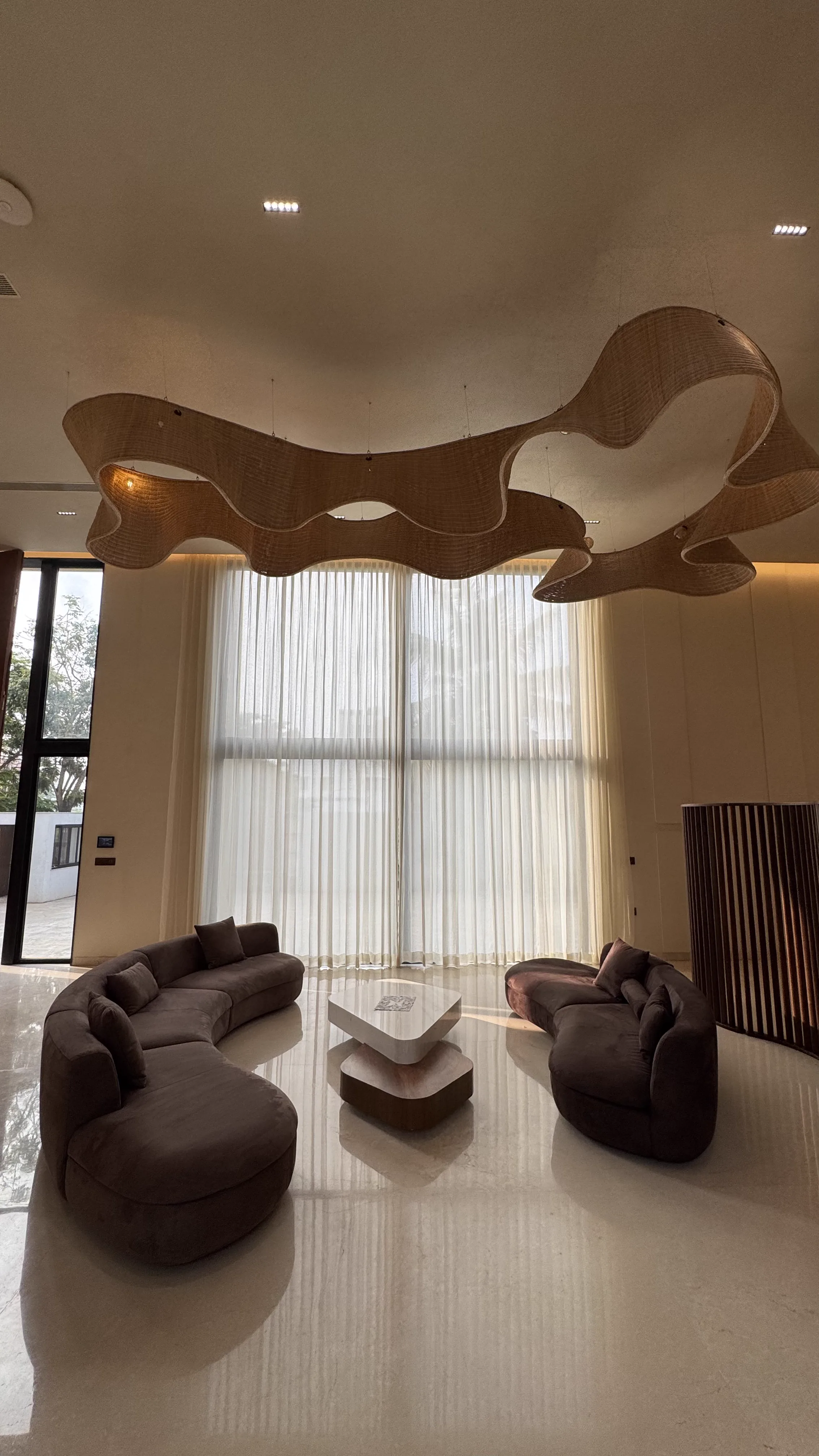 Curved brown sofas under a sculptural ceiling