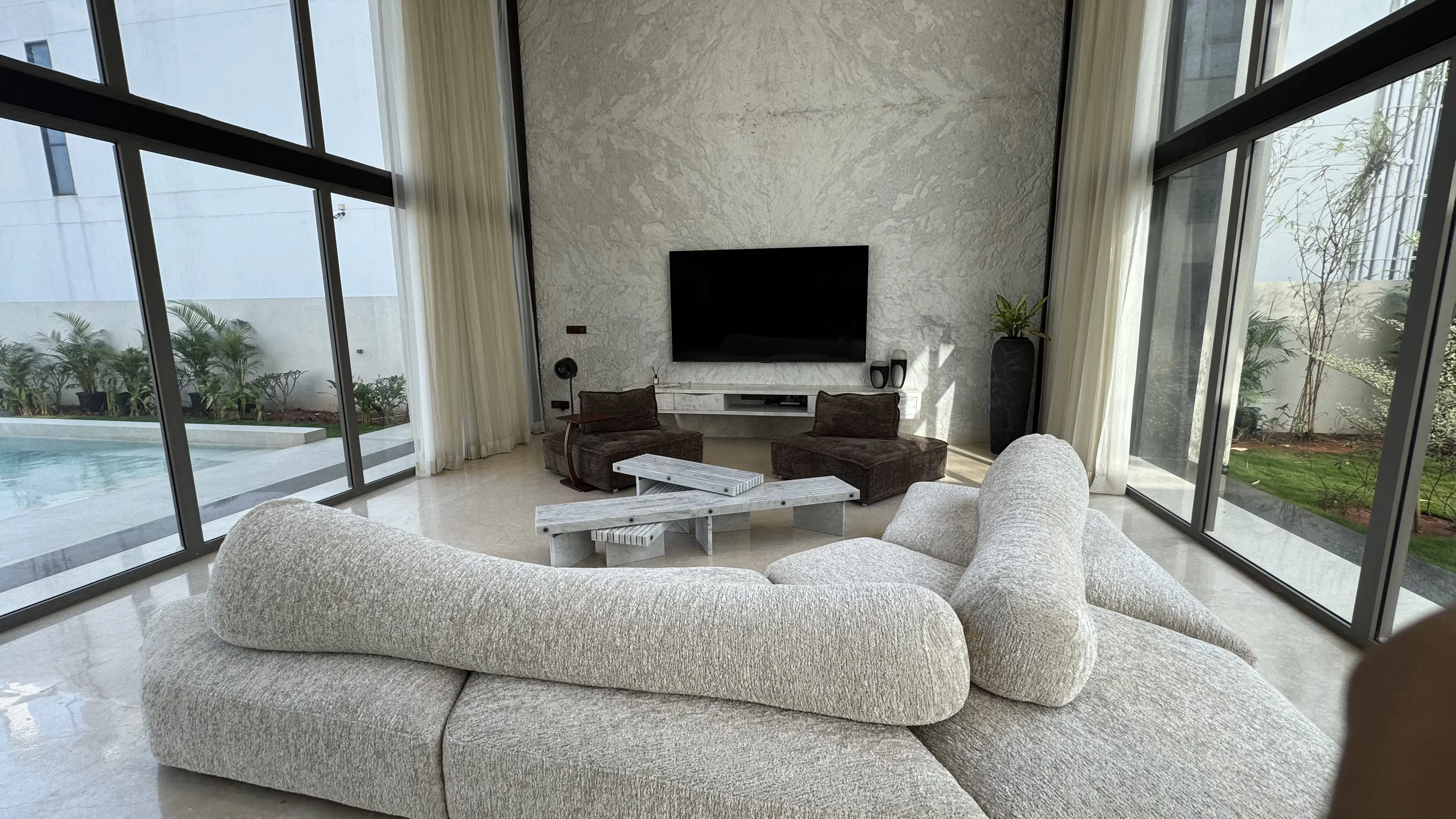 Curved brown sofas under a sculptural ceiling