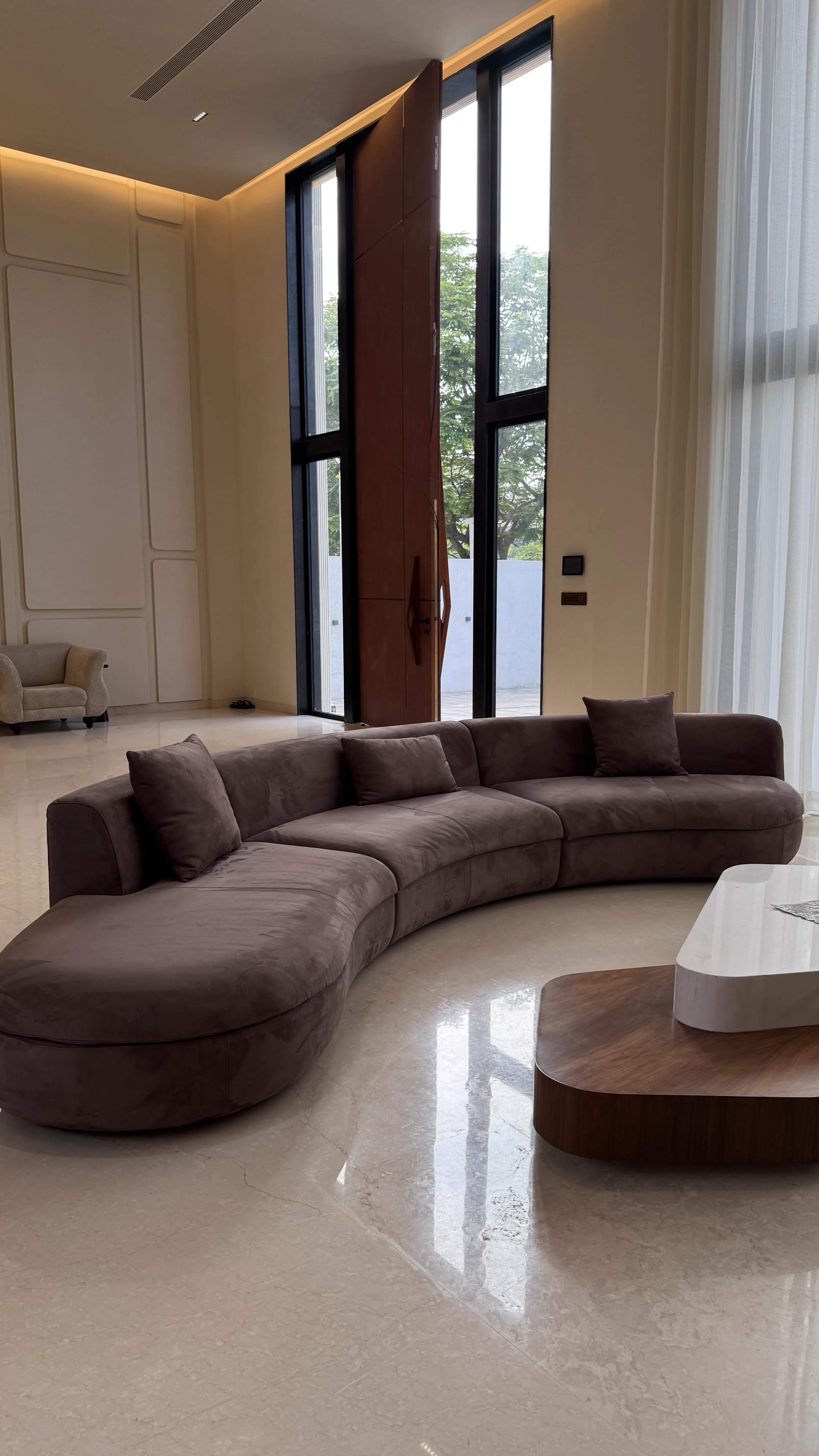 Brown curved modular sofa in a marble-floored living room