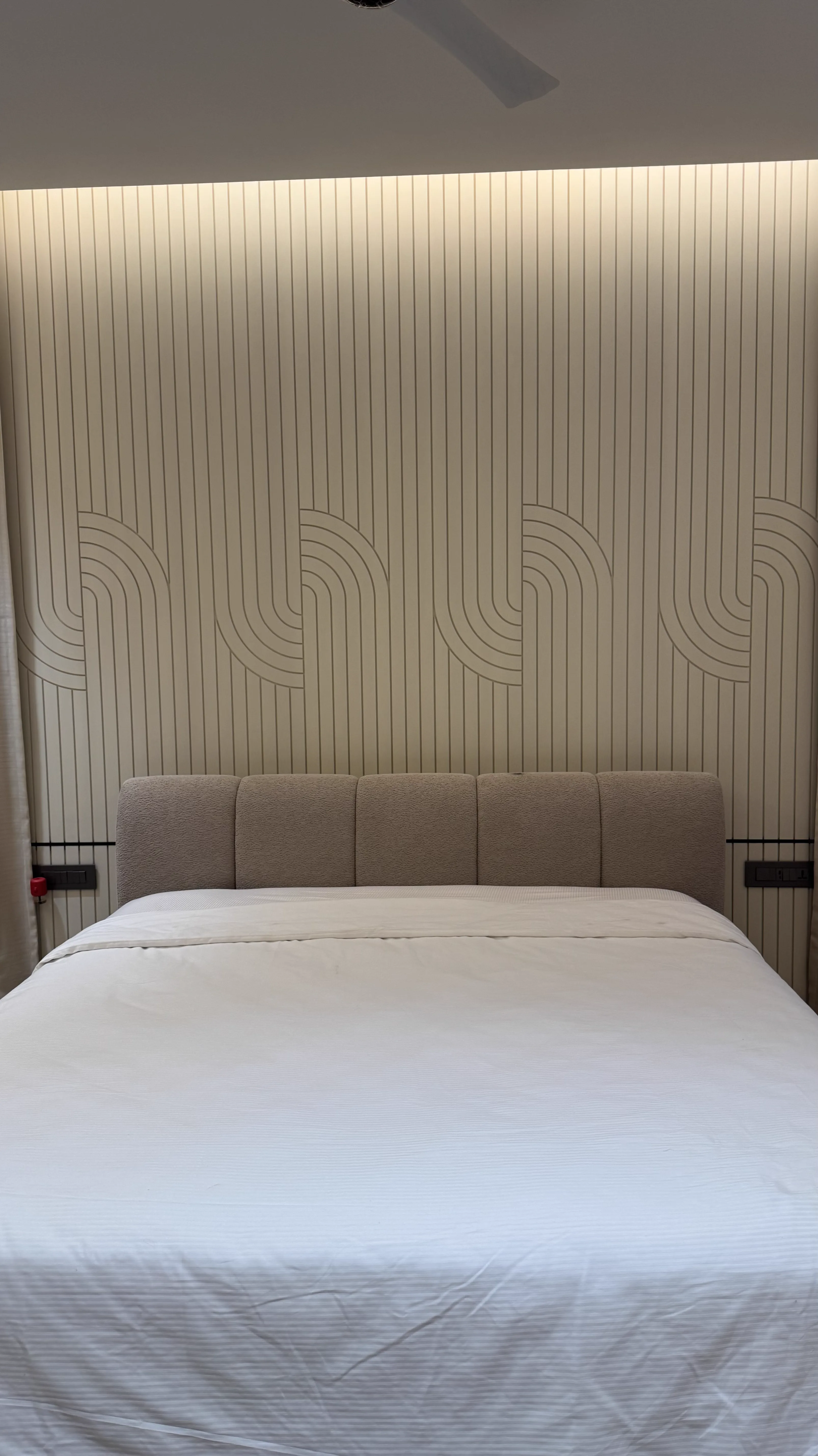 Fluted wall panelling with cove lighting behind an upholstered bed