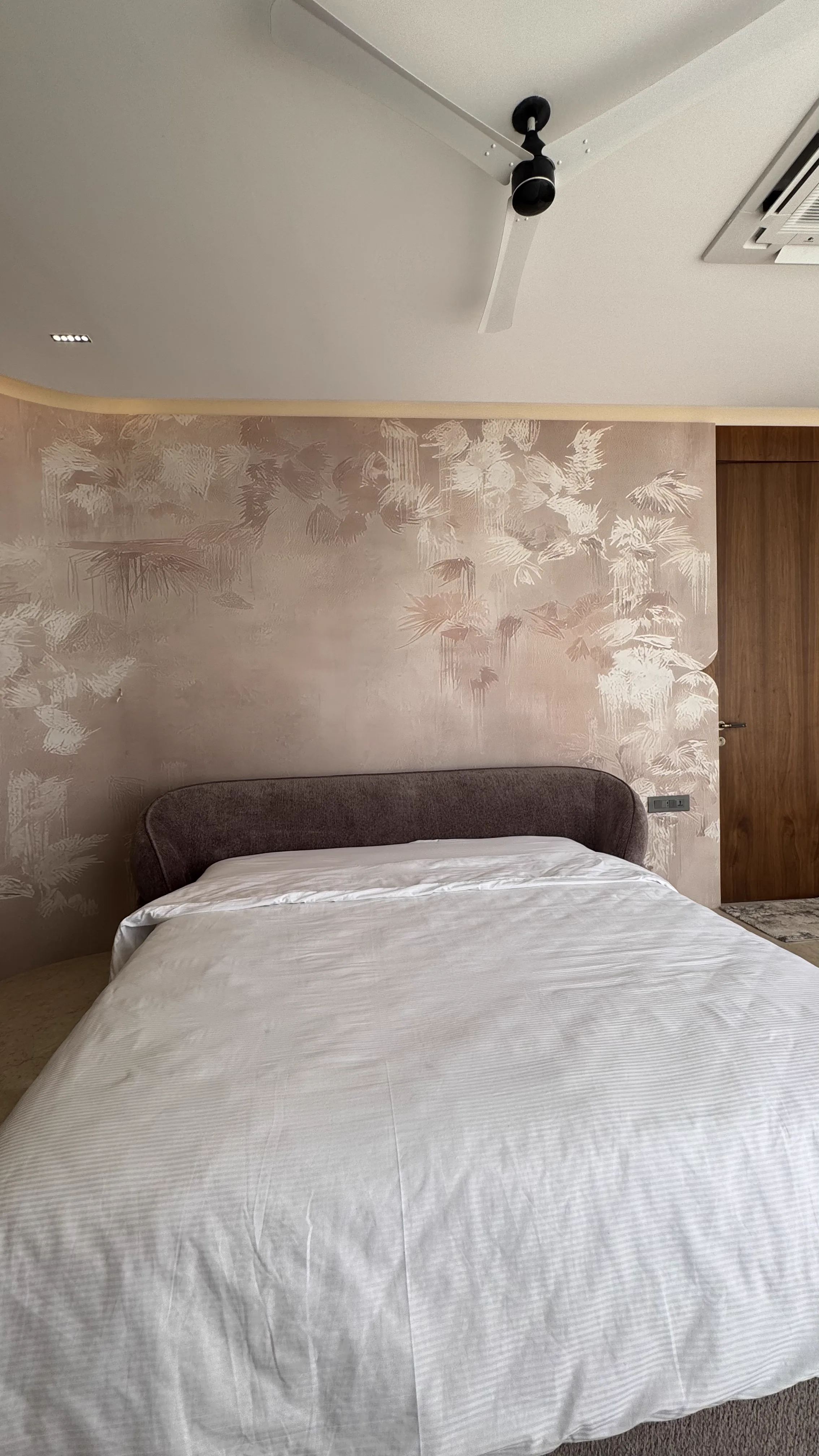 Textured feature wall behind a white bed
