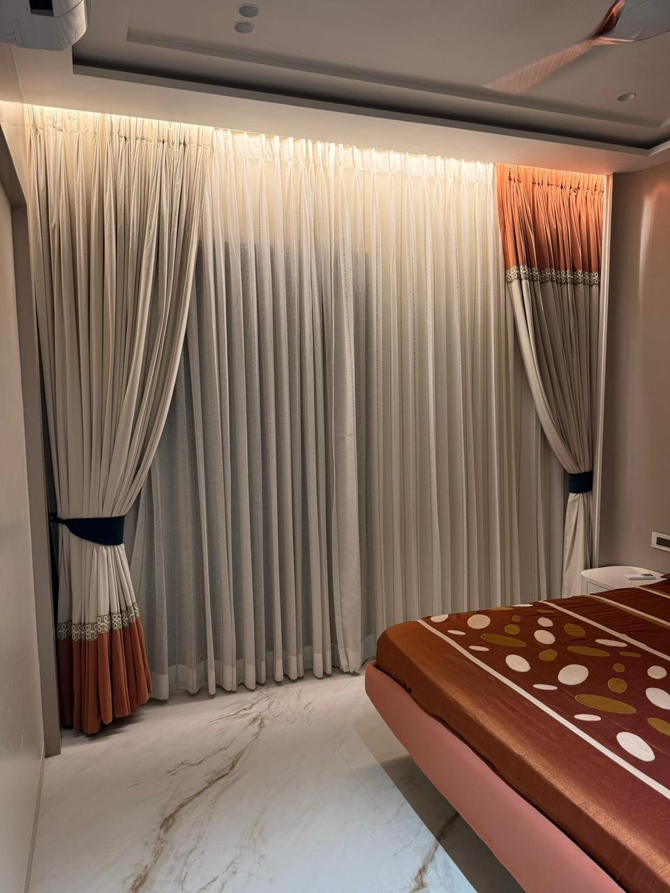 Cream pleated curtains with rust border and navy tie-backs