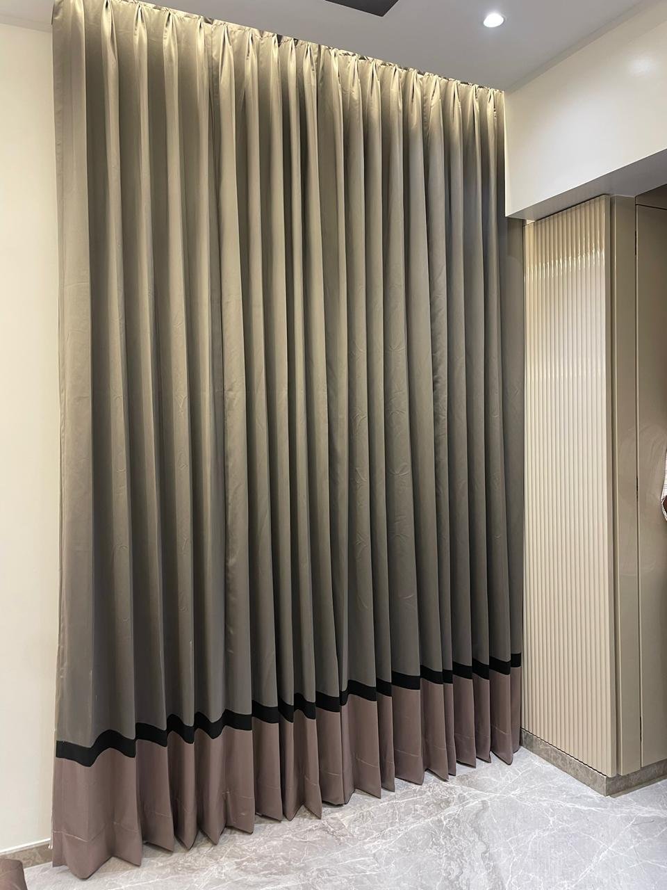 Grey satin blackout curtains across a wide window