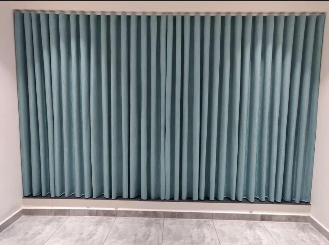 Teal ripple-fold curtains along a full wall