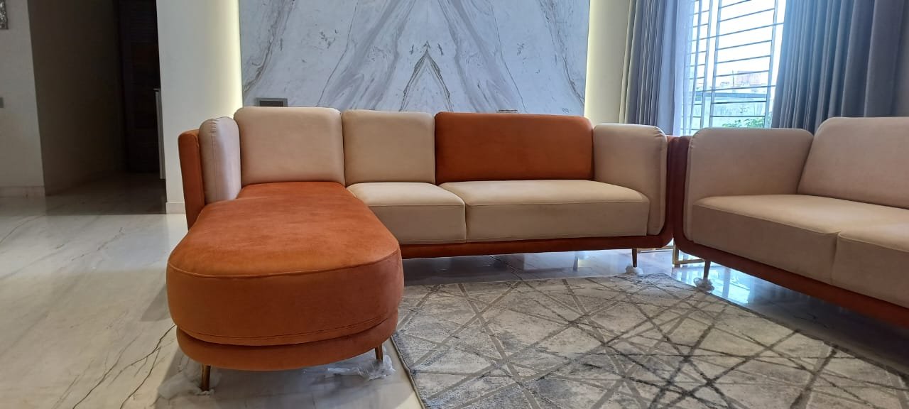 Cream and rust two-tone sofa set with a curved chaise by a marble wall